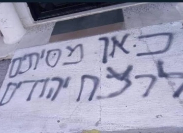 Settlers take slogans on the walls of a mosque in Deir Dabwan