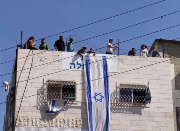 Settlers take over the roof of a house in Hebron