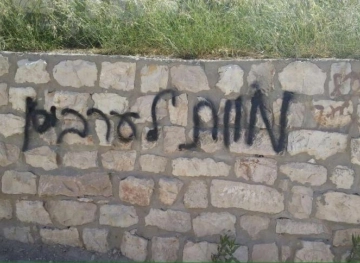 Settlers burn a vehicle and write racist slogans in Taybeh and Deir Ammar