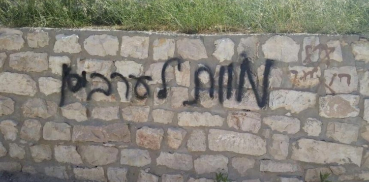 Settlers burn a vehicle and write racist slogans in Taybeh and Deir Ammar